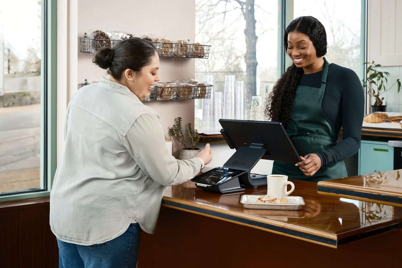 A customer paying at a shop counter while the cashier smiles.